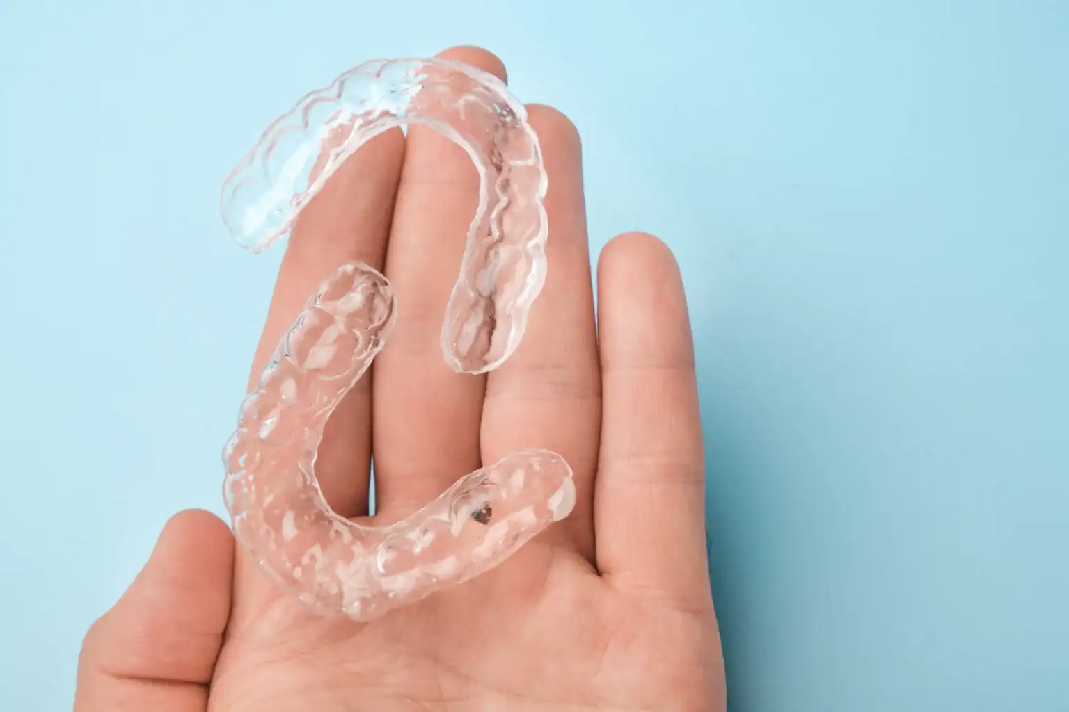 Hand holding clear dental aligners for orthodontic treatment at Main Street Dental Center in Collegeville, PA